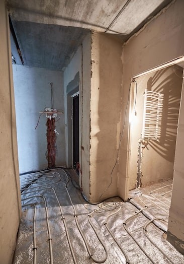 Before: raw construction hallway with exposed plumbing and wiring